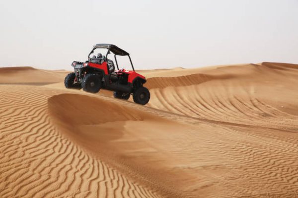 Off-road SUV vehicle speeding through sand dunes in the Arabian desert